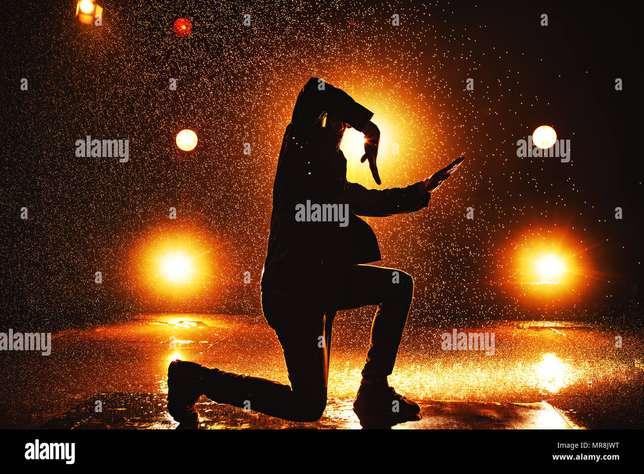 Joven bailarina ruptura dramática silueta en el club con luces y agua Foto de stock