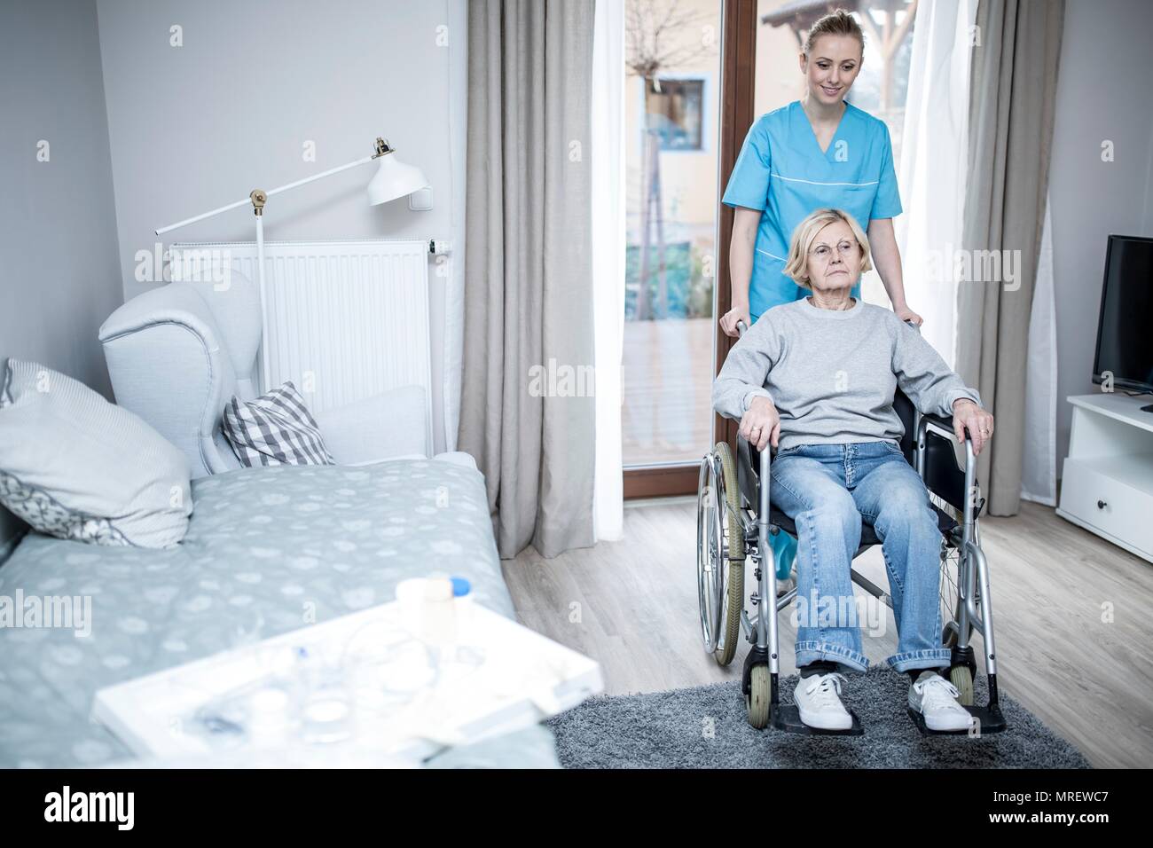 Mujer mayor en silla de ruedas con cuidado trabajador de cuidado en casa. Foto de stock
