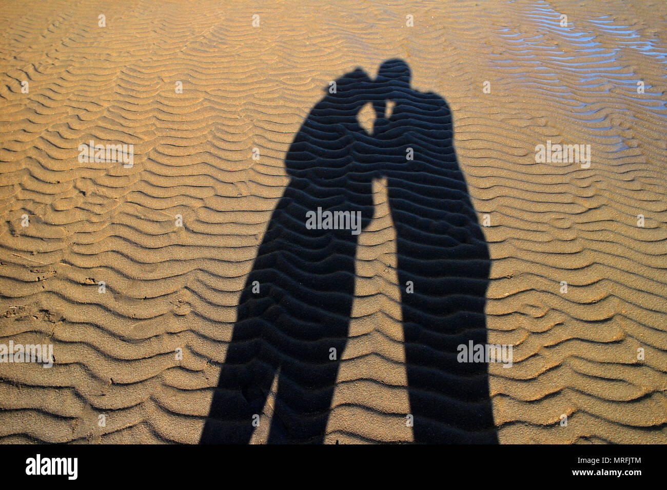 Sombra de dos personas besándose mutuamente en la playa. Foto de stock