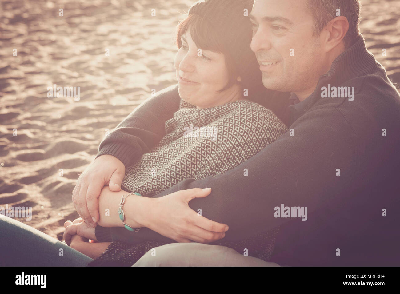 Preciosas La edad media de 40 años de edad par hombre y mujer caucásica se abrazaron y permanecer juntos en la playa, sentado en la arena y disfrutar de un golde un Foto de stock