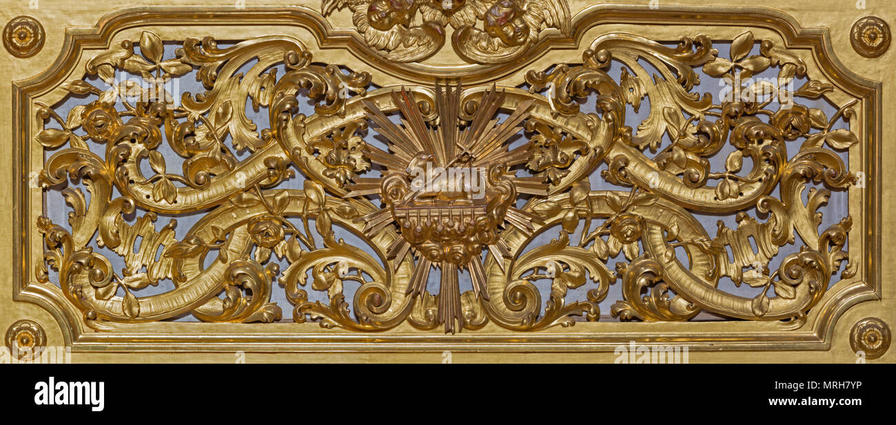 MODENA, Italia - 14 de abril de 2018: el alivio de la policromía barroca tallada sobre el altar con el Cordero de Dios en el ceter en la iglesia Chiesa di San Barnaba. Foto de stock