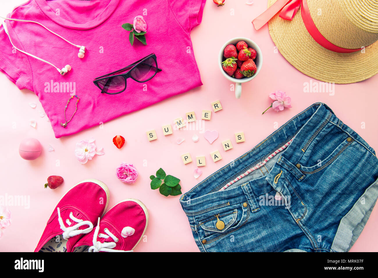 Concepto de planificación de verano femenina - ropa, accesorios, flores y fresas sobre fondo de color rosa. La moda -T-shirt, denim shorts, zapatillas, s Fotografía de stock Alamy