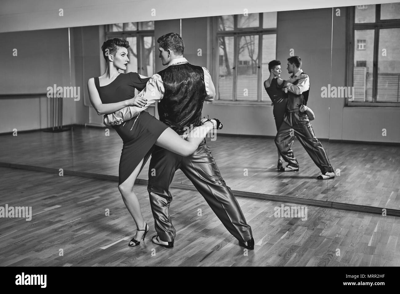 Hermosa pareja bailando tango. mujer joven en vestido rojo y el hombre en traje practicando en estudio de baile sala de espejo. Copie el espacio Fotografía de stock - Alamy Hermosa pareja bailando tango. mujer joven en vestido rojo y el hombre en traje practicando en estudio de baile sala de espejo. Copie el espacio Fotografía de stock - Alamy