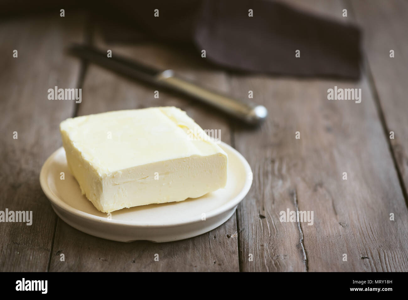 Mantequilla sobre fondo de madera oscura, copie el espacio. Granja de productos lácteos - mantequilla. Foto de stock
