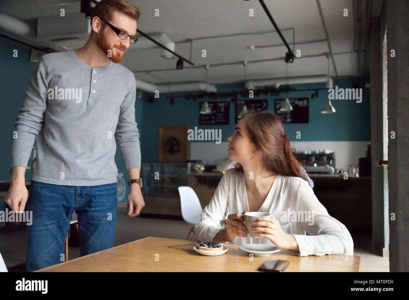 Hombre viniendo a la mesita de café que familiarizarse con bella mujer Foto de stock