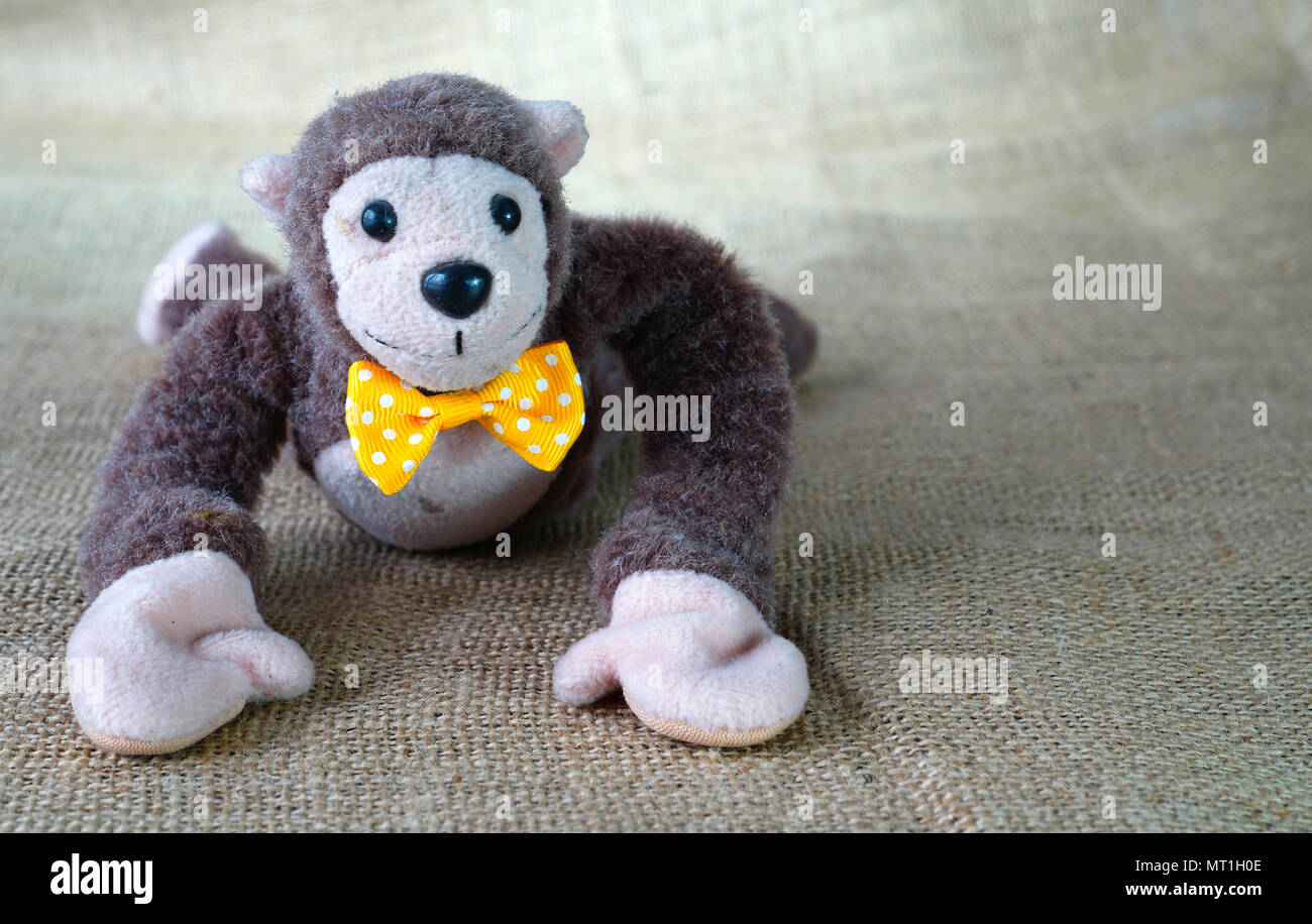 Lindo mono juguete blando con pajarita amarilla acostado en el piso  Fotografía de stock - Alamy