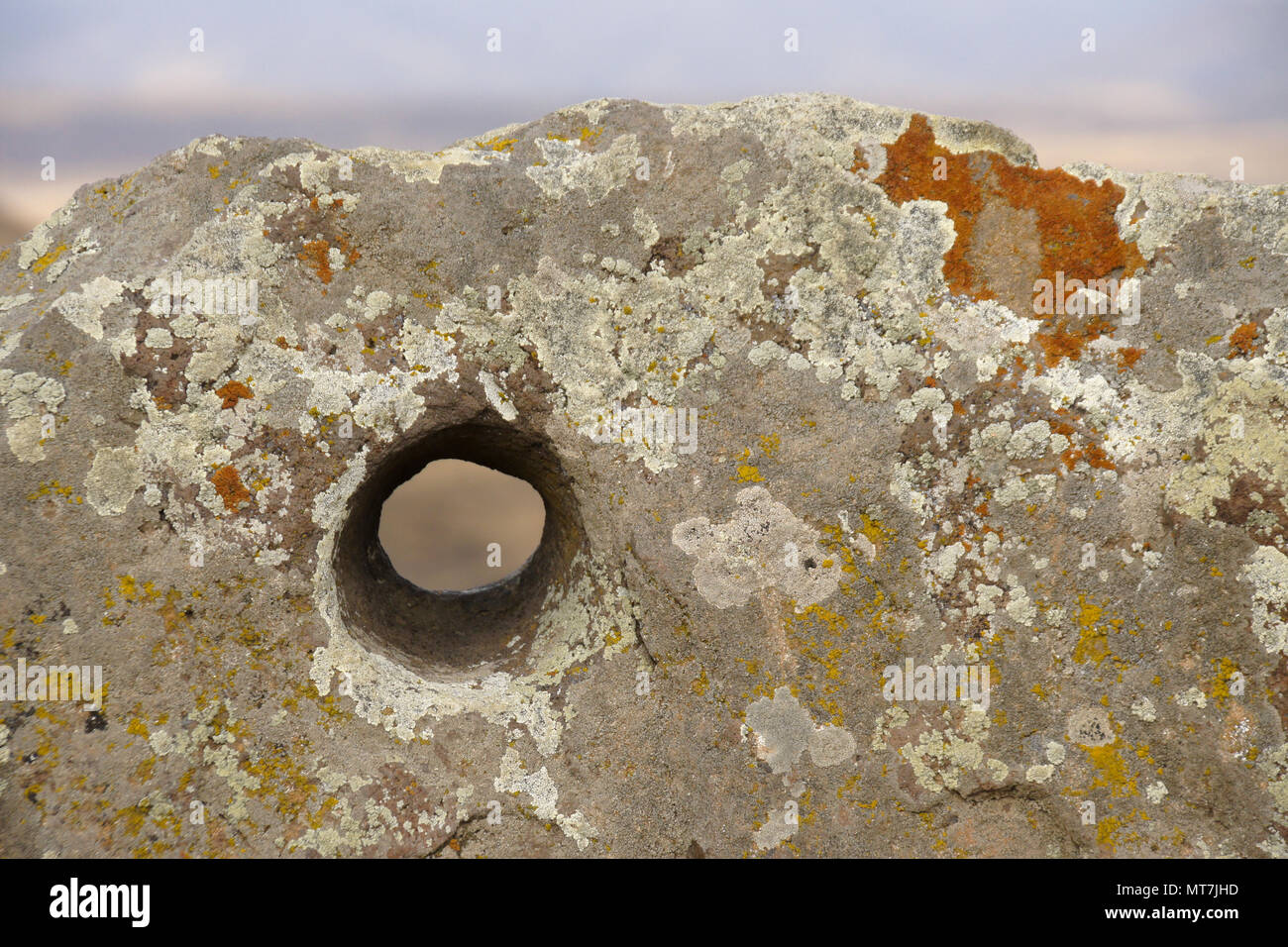 Liquen de roca incrustada con agujero aburrió, Carahunge Karahunj (Observatorio) cerca de la ciudad de Sisian, Armenia Foto de stock