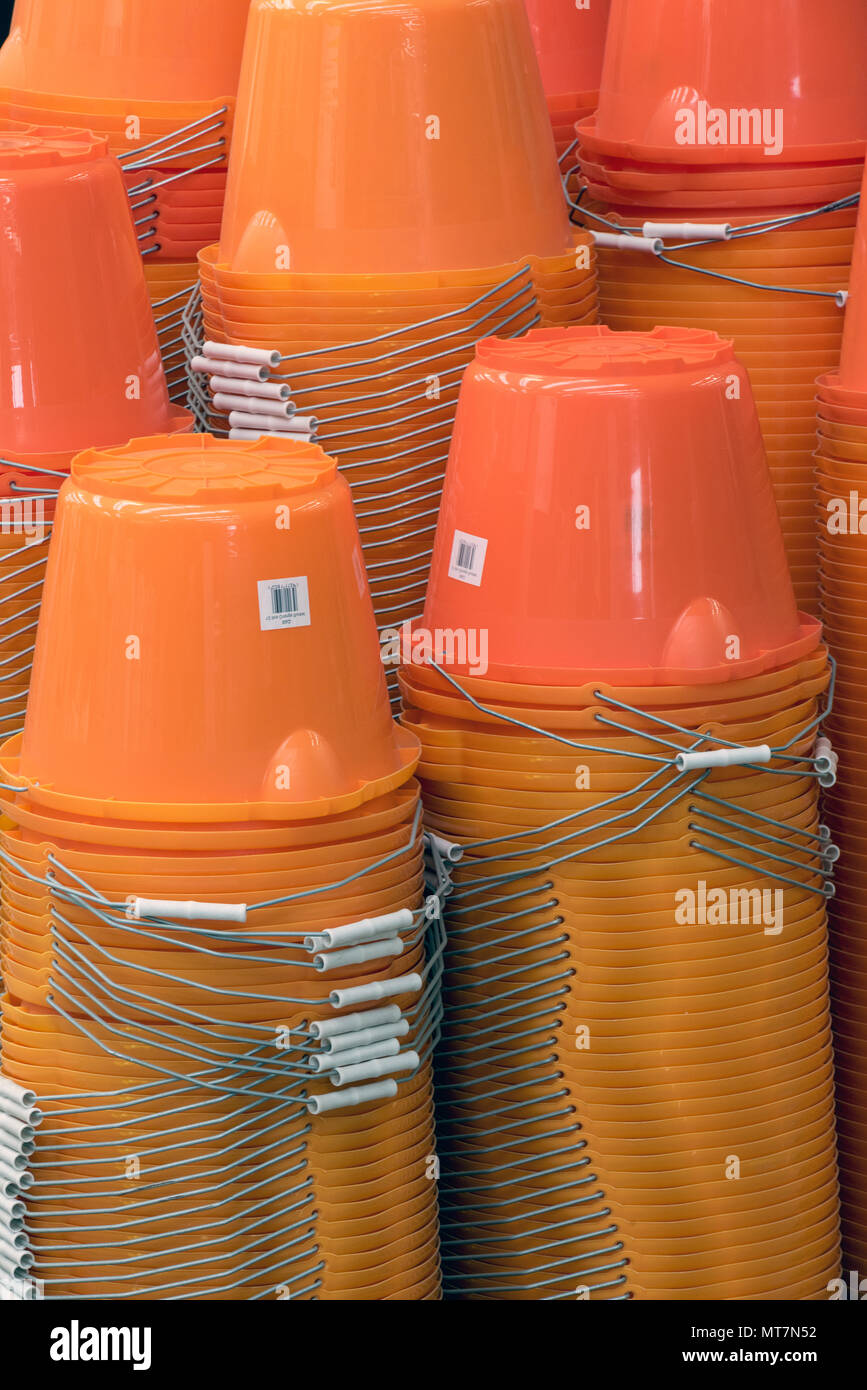 Un montón de cubos de plástico naranja en una pila para la venta en un importante distribuidor de hardware High street b y q. Transformador inyección de plásticos para uso doméstico