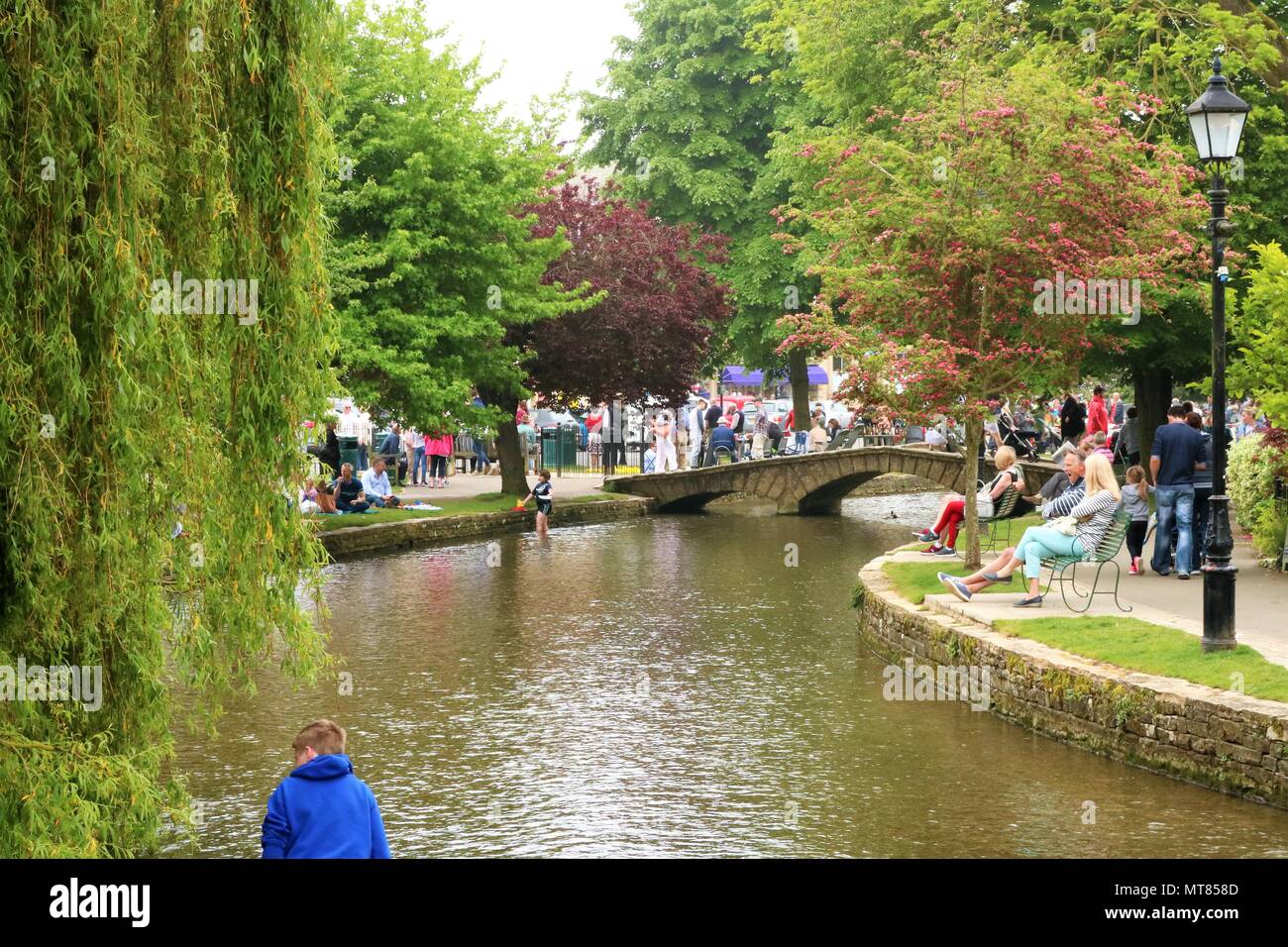 La gente disfruta del mayo festivo en Bourton sobre el agua, Gloucestershire, Reino Unido dentro de los Cotswolds, Zona de Excepcional Belleza Natural Foto de stock
