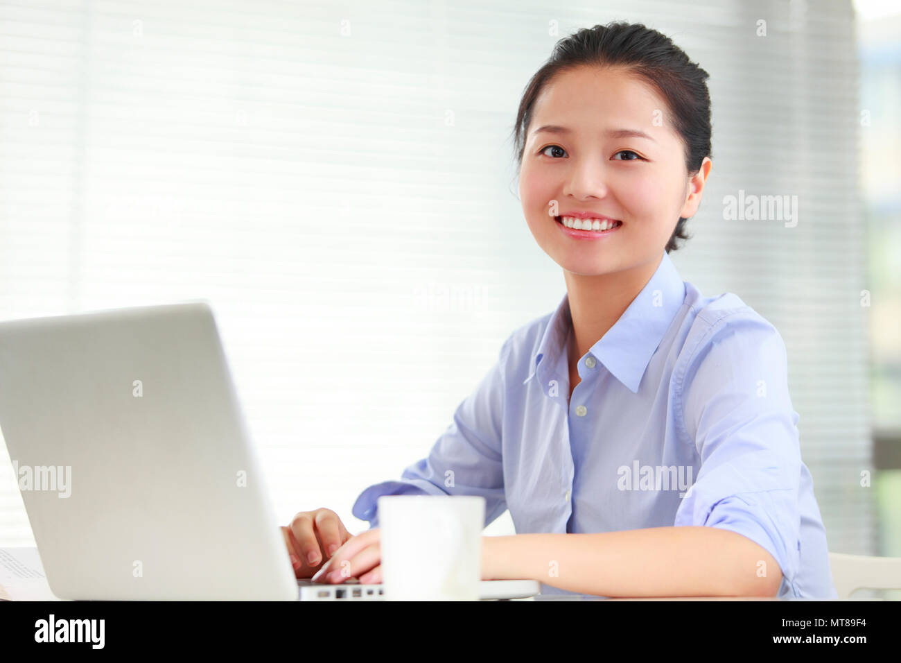 Una joven mujer de negocios asiáticos usando el portátil en la oficina Foto de stock