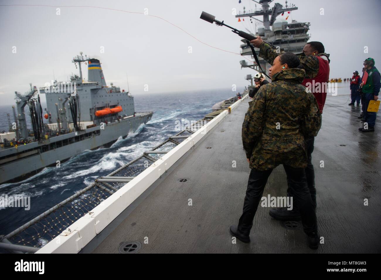 180514-N-OY799-0095 las aguas al sur de Japón (14 de mayo de 2018) El Gunner's Mate Seaman Elías Reid, derecho, desencadena un mensajero a la línea de comando de Transporte Marítimo Militar (MSC) lubricador de reposición de flota Tippecanoe USNS (T-AO 199) de la cubierta de vuelo a bordo de la Marina desplegadas, el portaviones USS Ronald Reagan (CVN 76), como parte de una reposición en alta mar durante las pruebas de mar. Los civiles no combatientes, con tripulación de barco, operado por la MSC, proporciona el combustible, alimentos, municiones, piezas de repuesto, el correo y otros suministros a los buques de la Marina en todo el mundo. Ronald Reagan, el buque insignia de Carrier Strike Group 5, proporciona una comba Foto de stock