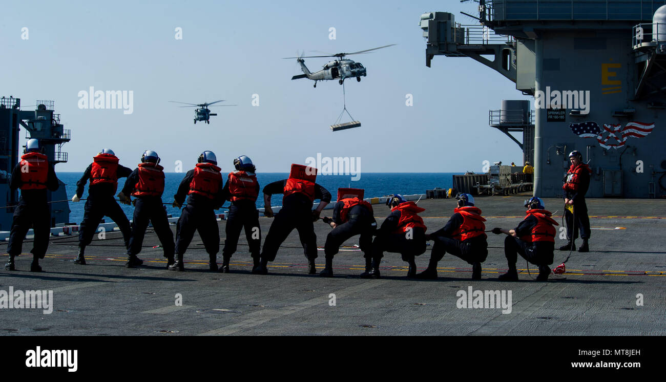 180515-N-OY799-0290 las aguas al sur de Japón (15 de mayo de 2018) Los marineros de cubierta departamento hombre el teléfono y distancia en línea de la cubierta de vuelo como MH-60S mar, halcones, asignado al comando de Transporte Marítimo Militar (MSC) carga seca/municiones buque USNS César Chávez (T-AKE 14), entregar explosivos a la Marina desplegadas, el portaviones USS Ronald Reagan (CVN 76), como parte de una reposición en alta mar durante las pruebas de mar. Los civiles no combatientes, con tripulación de barco, operado por la MSC, proporciona el combustible, alimentos, municiones, piezas de repuesto, el correo y otros suministros a los buques de la Marina en todo el mundo. Ronald Reagan, el buque insignia de coche Foto de stock