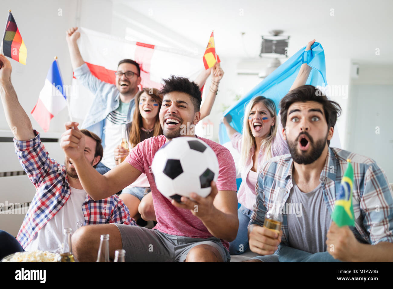 Alegre grupo de amigos viendo partido de fútbol en la televisión. Foto de stock