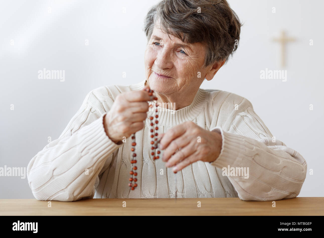 Retrato de la abuela sonriendo con rojo rosario rezando en la iglesia