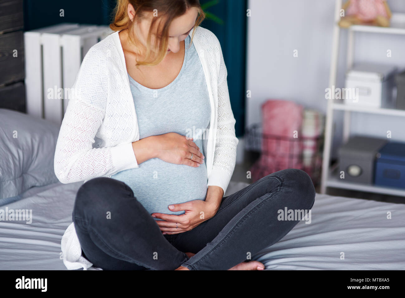 Mujer embarazada afectuoso tocando su vientre en casa Foto de stock
