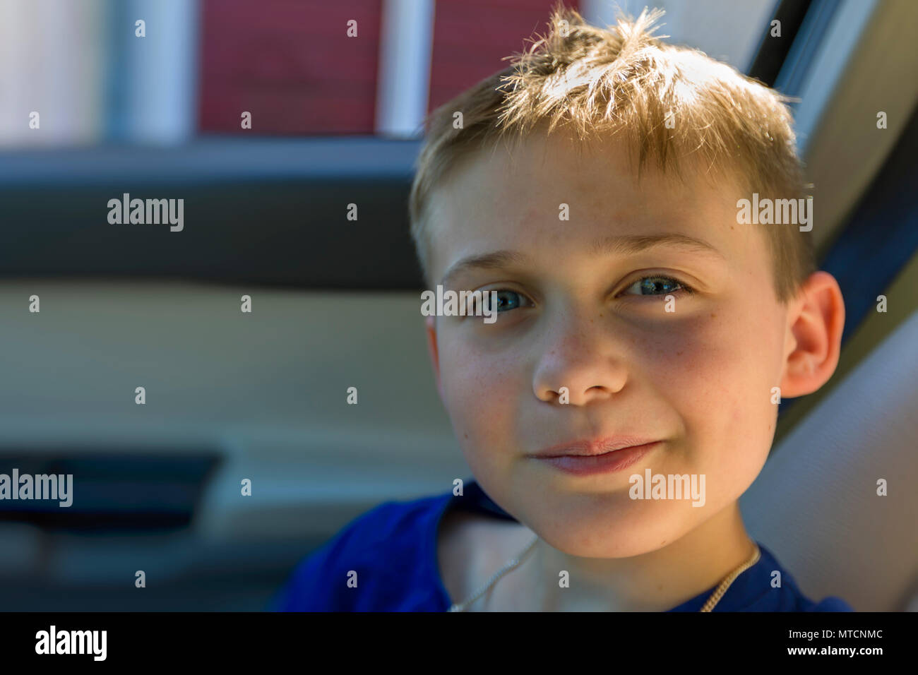 Vista cercana retrato de lindo joven muchacho caucásico de 10 años de edad en el asiento del pasajero coche mirando y sonriendo a la cámara Foto de stock