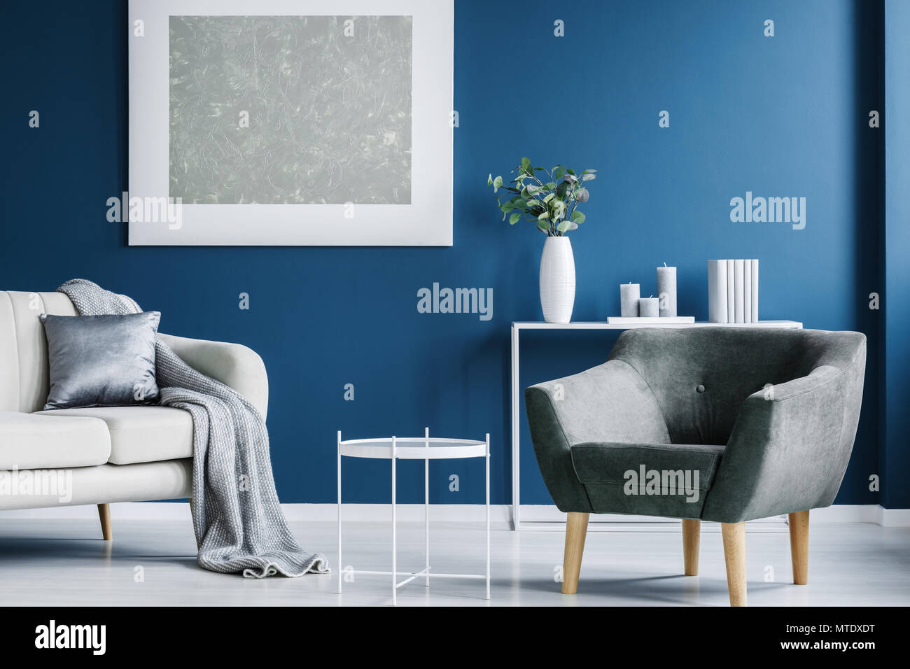 Metal gris mesa de café, sillón, sofá color blanco con una manta y una  almohada, y una gran pintura en la pared azul en una sala interior  Fotografía de stock - Alamy