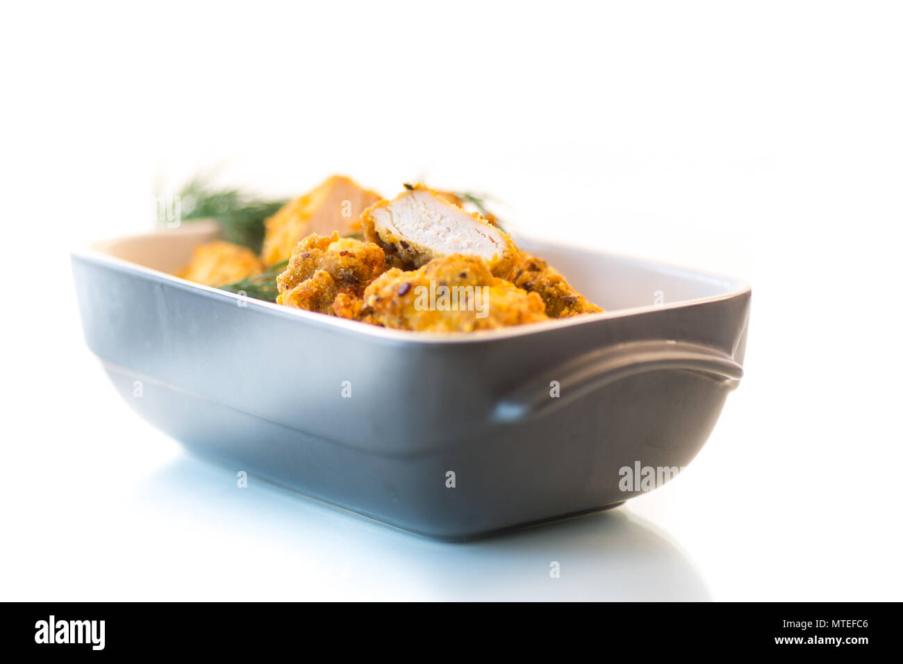 Pollo frito rebozado con eneldo en forma de cerámica sobre un fondo blanco. Foto de stock