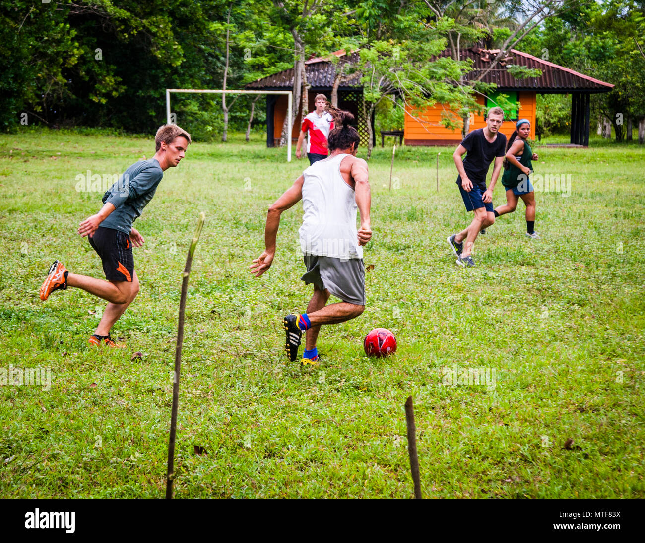 Elenco internacional improvisado partido de fútbol en Costa Rica. El idioma del fútbol no conoce fronteras. Con los lugareños que guían a los voluntarios a lo largo de la playa por la noche en nombre del proyecto de investigación, les gusta organizar reunirse en el campo de fútbol durante el fin de semana Foto de stock