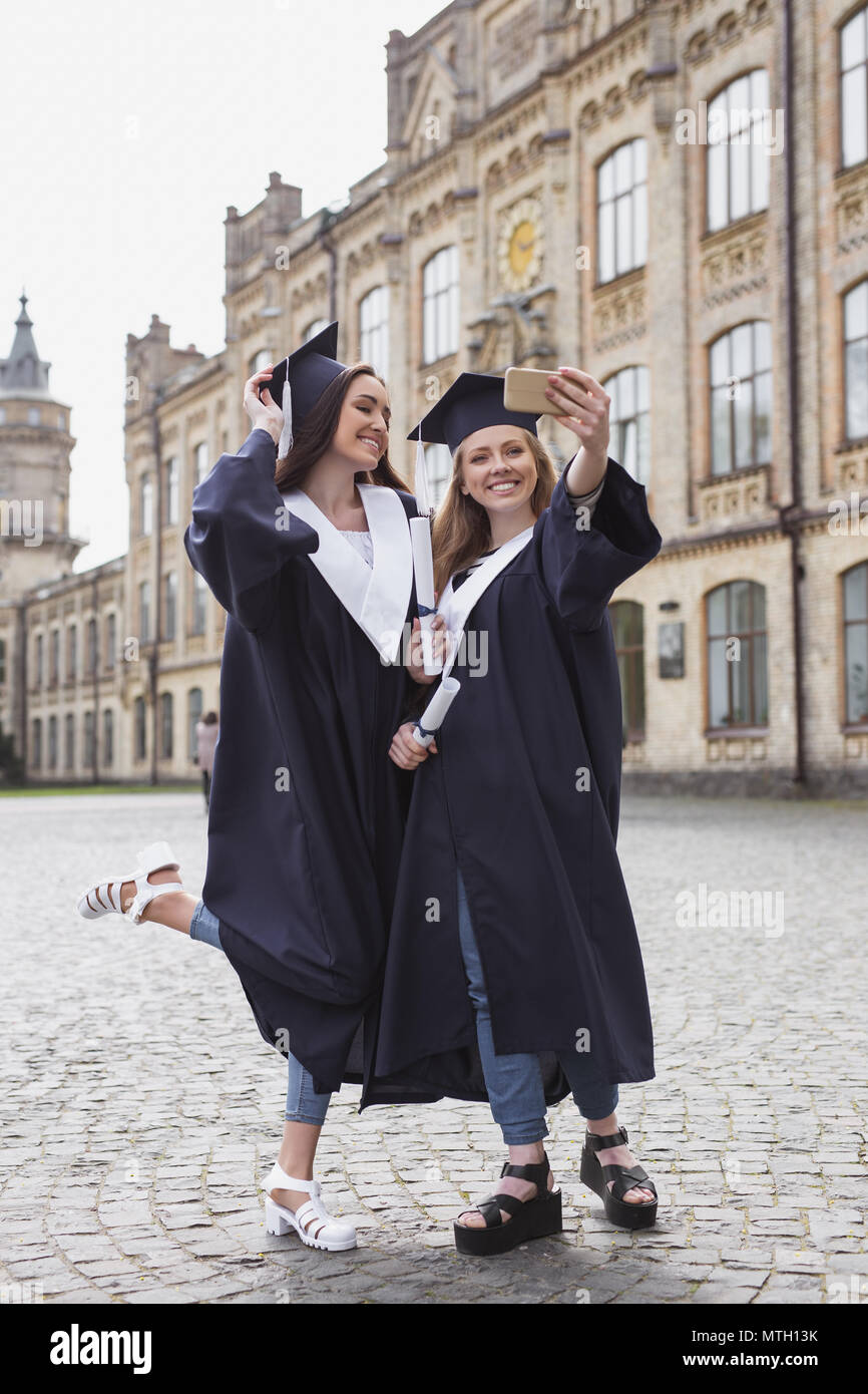 Dos hermosas chicas en trajes de graduación posando para la foto Fotografía de stock -