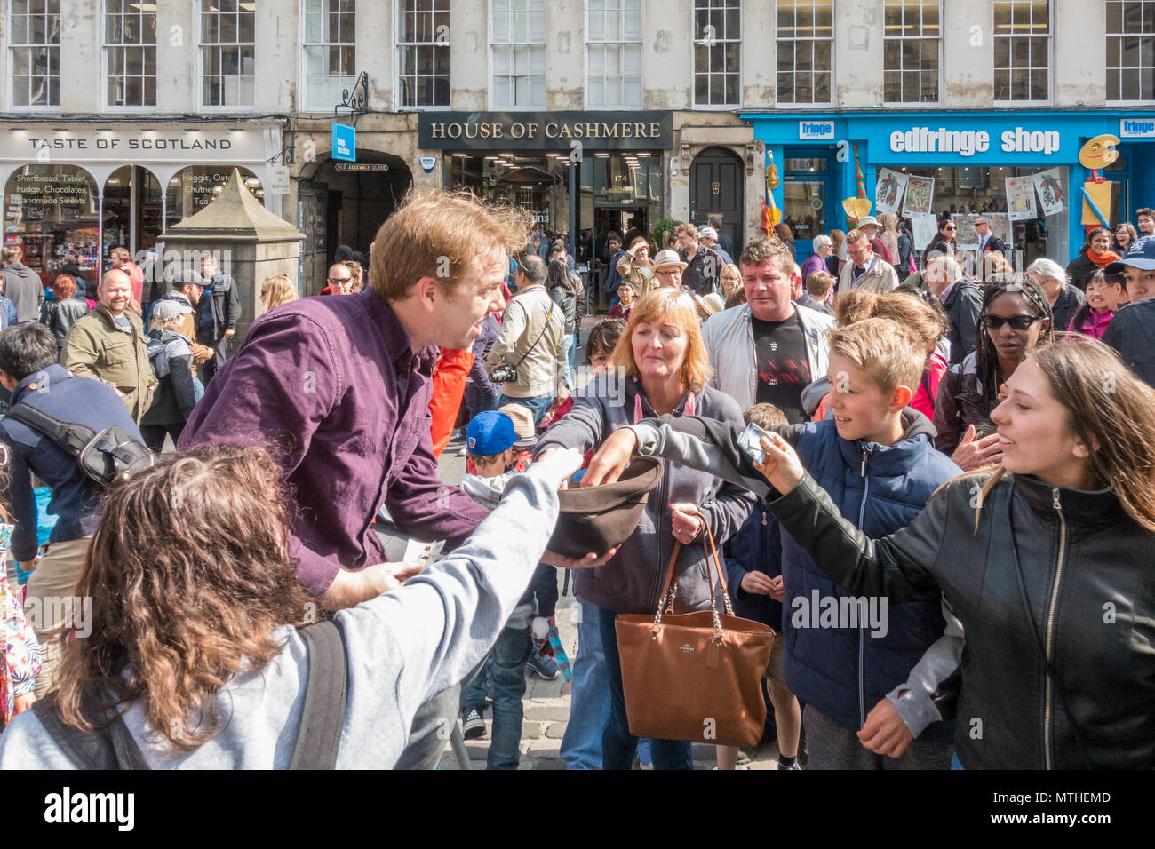 Entusiasta multitud de personas pagando dando dinero a un ejecutante de la calle en la Royal Mile, Edimburgo, Escocia, Reino Unido Foto de stock