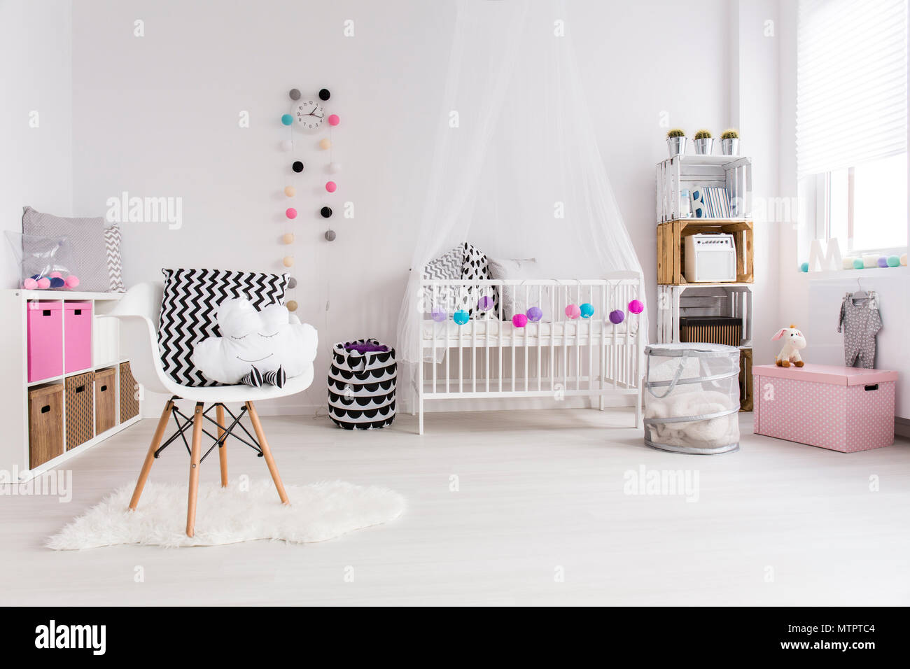Dormitorio blanco diseñado para bebé niña. Por la pared cuna con dosel,  estantería y juguetes. En el oriente blanco sillón con almohadas Fotografía  de stock - Alamy