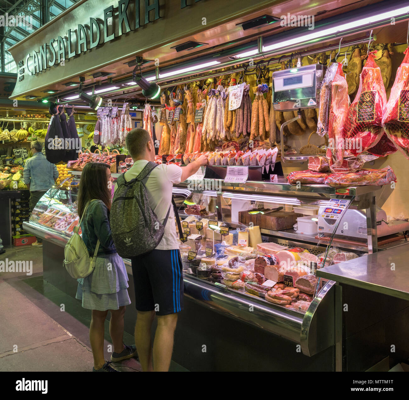 Pareja joven comprando en un puesto de comida en el Mercat de la Boqueria, Barcelona, Cataluña, España. Foto de stock