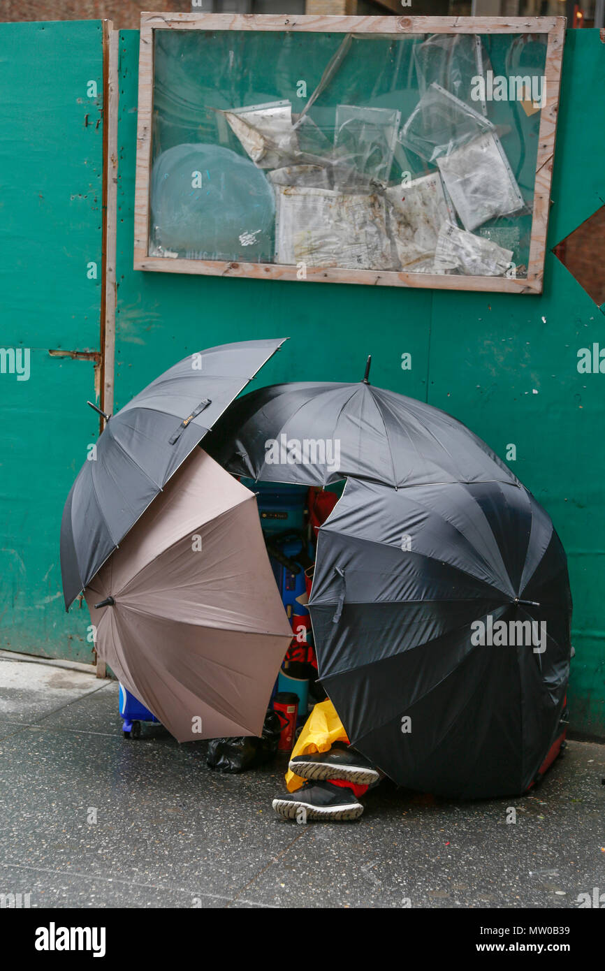 Creative persona sin hogar construye una carpa en la acera con sombrillas  para salir de la lluvia en el centro de Manhattan, en la ciudad de Nueva  York Fotografía de stock -