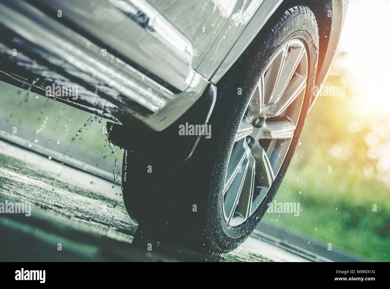 Coche en la lluvia. Lluvia moderna Verano neumáticos en el pavimento mojado. Closeup Aquaplaning foto. Foto de stock
