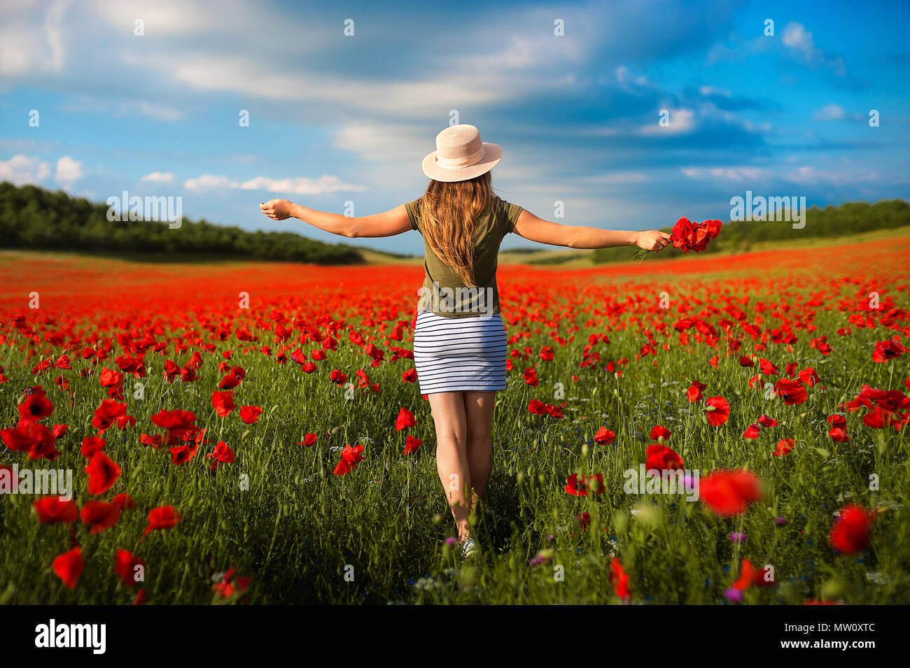 Retrato de hermosa mujer joven en el campo de amapolas rojas Foto de stock