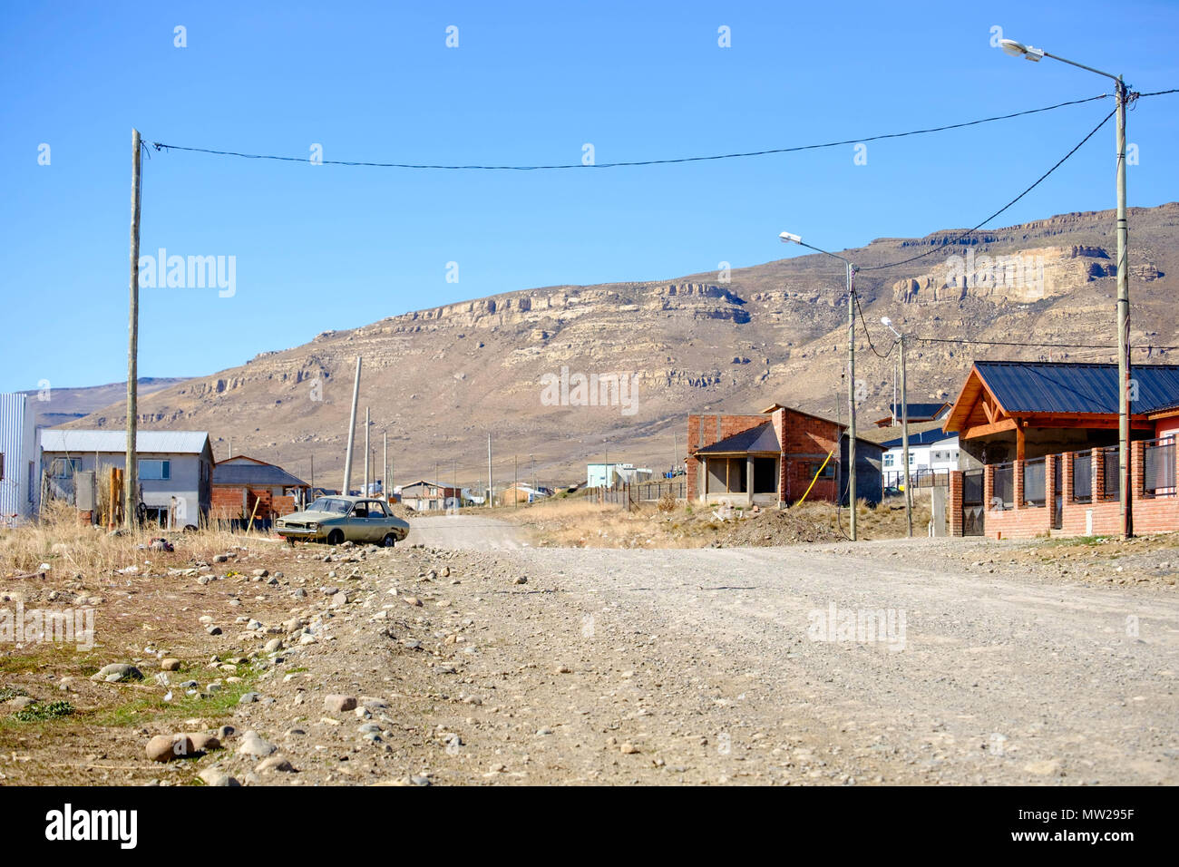 Cuando se llega a las afueras de El Calafate en la Patagonia Argentina, se ven caminos polvorientos como éste, con algunas casas a lo largo de la carretera. Foto de stock