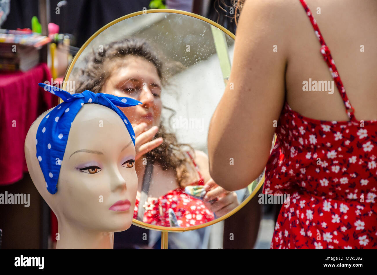 Un adulto joven se mira a sí misma en un espejo en un puesto en el mercado. Foto de stock