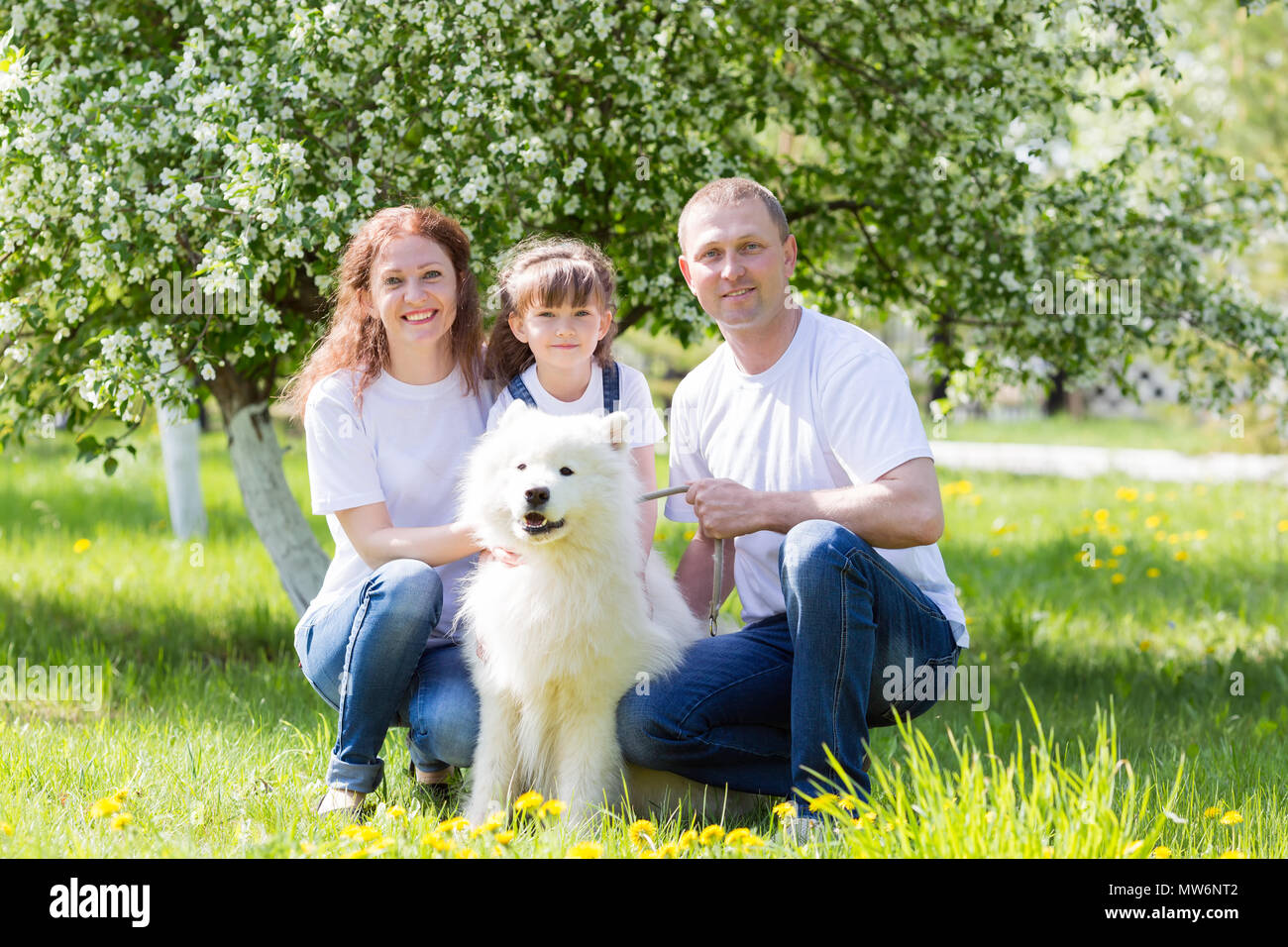 El esposo, la esposa y la hija en ropa blanca y jeans, junto con un perro  blanco, descansar en el jardín Fotografía de stock - Alamy