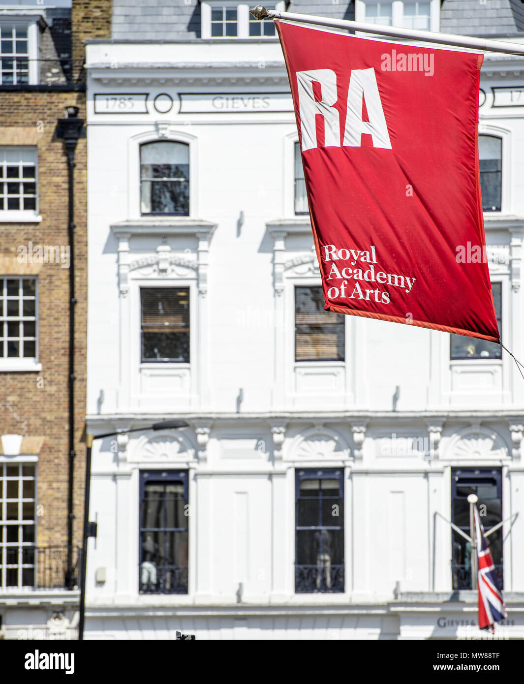 El sol brilla en la bandera de la Royal Academy of Arts, ya que cuelga frente al edificio en Savile Row, en el centro de Londres Foto de stock