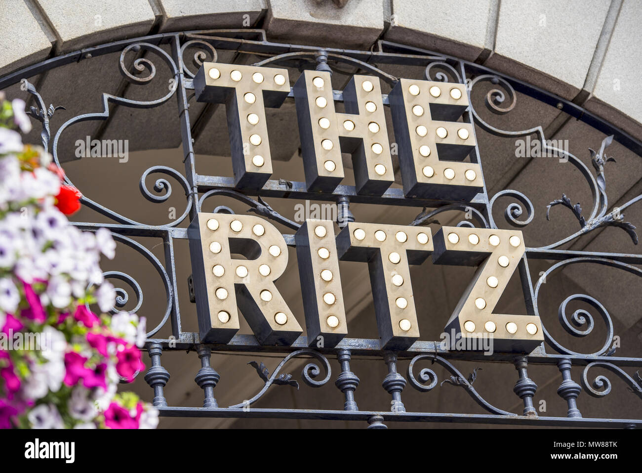 La icónica señalización de estilo Art Decó en el hotel Ritz, Londres, en el corazón de Mayfair, con flores de verano en primer plano Foto de stock