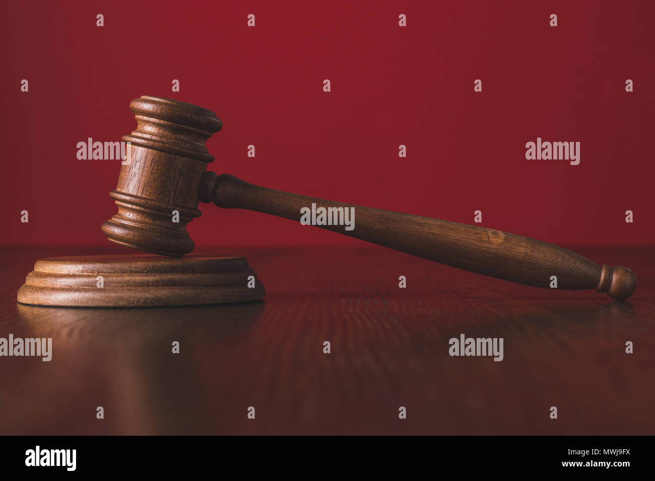 Las sentencias sobre la madera martillo mesa enfrente de fondo rojo, el concepto de derecho Foto de stock