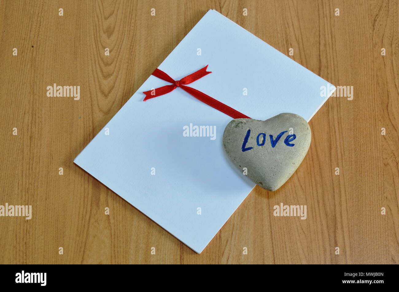 Corazón de Piedra de amarre sobre papel blanco cinta roja Fotografía de  stock - Alamy