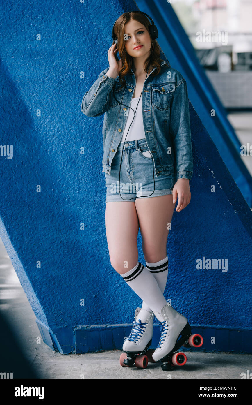 Moda Mujer joven en jeans y ropa retro patines escuchando música en  auriculares Fotografía de stock - Alamy