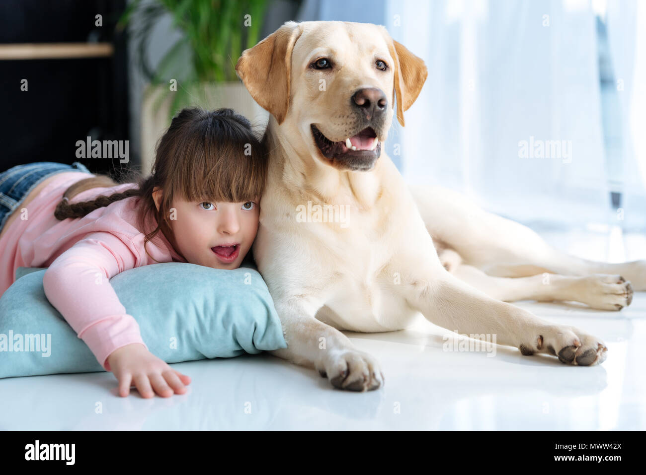 estación de televisión Ineficiente Calma Niño con síndrome de down tumbado en el suelo junto al perro Labrador  Retriever Fotografía de stock - Alamy