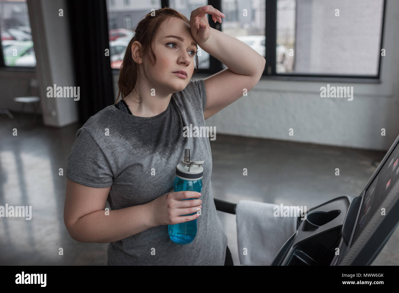 Curvilínea chica con la botella de agua en la caminadora en el gimnasio  Fotografía de stock - Alamy