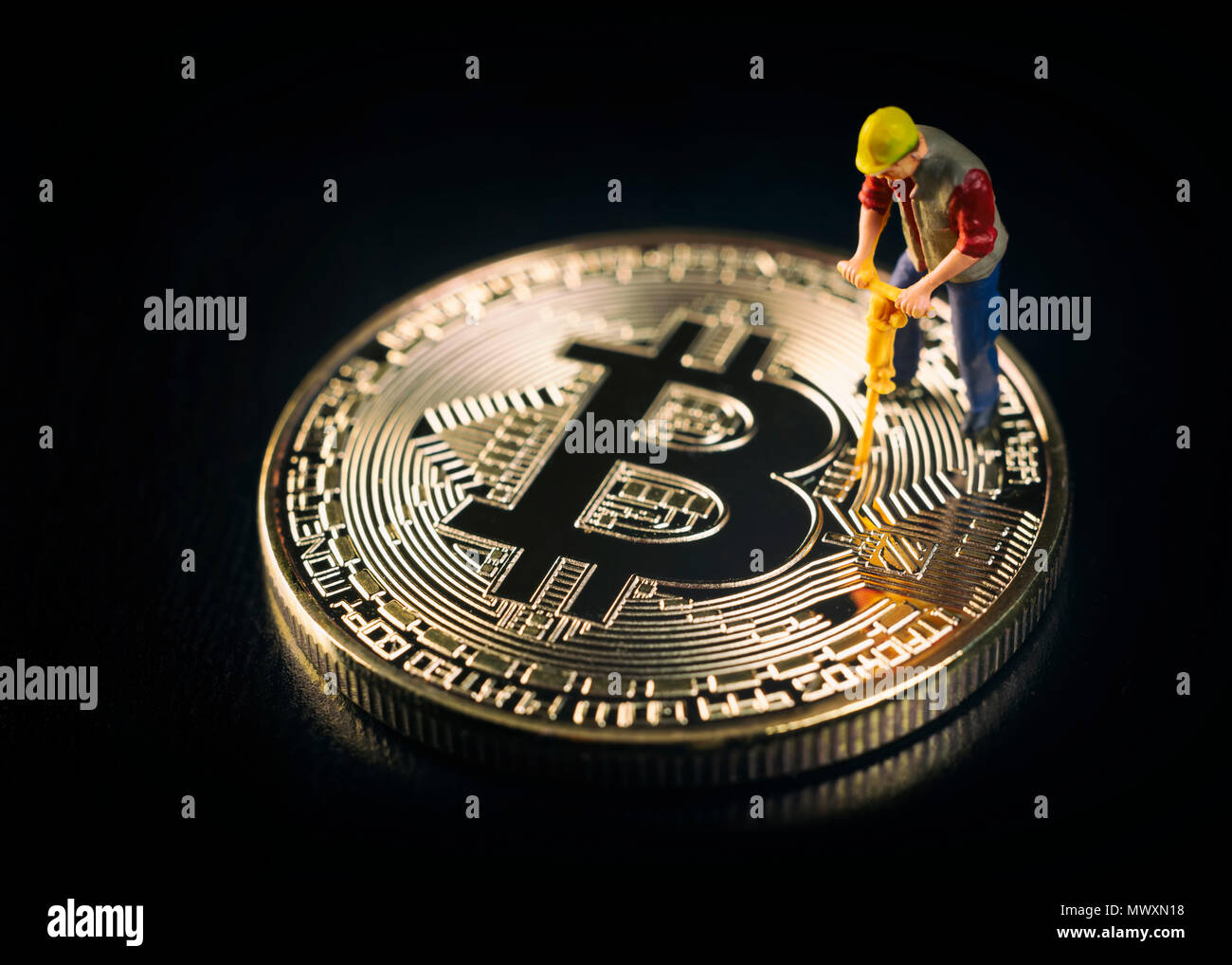 Trabajador en miniatura la minería Bitcoin sobre una superficie negra Foto de stock