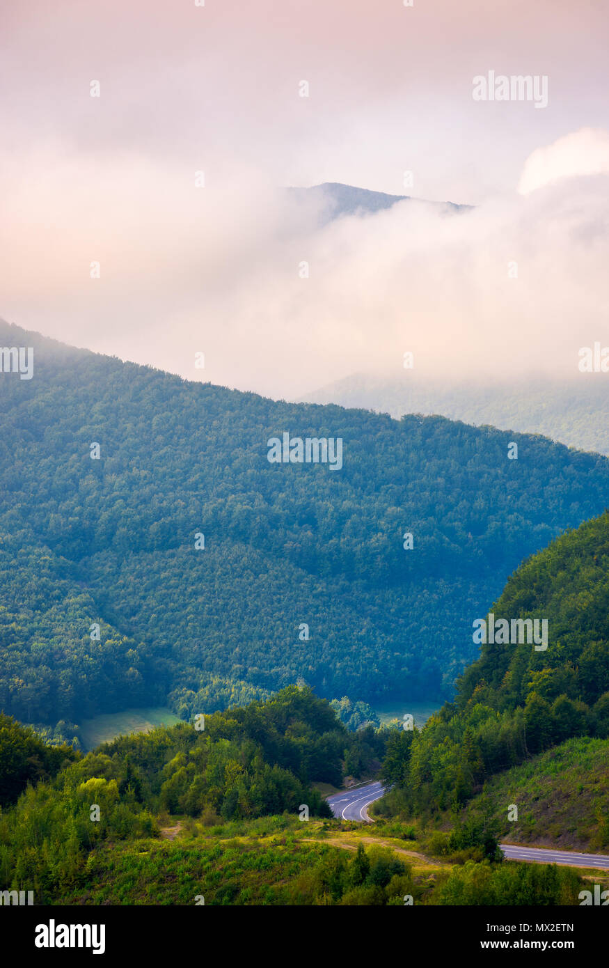 Hermoso paisaje de montaña en nubes bajas. Pico de la montaña en la distancia entre las nubes. Hermoso paisaje mañana Foto de stock