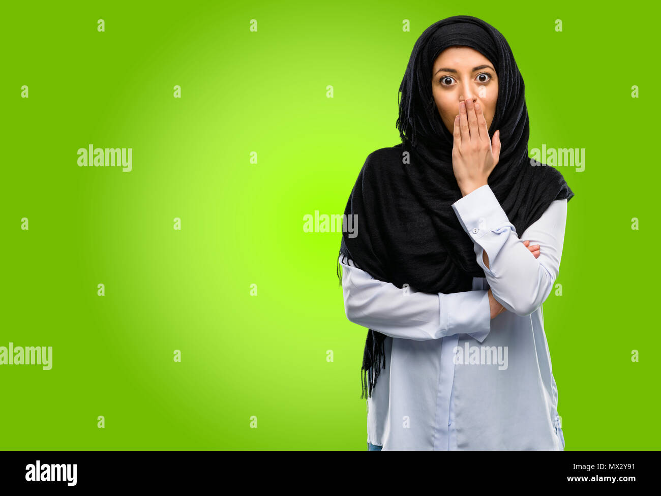 Joven árabe mujer vistiendo el hijab cubre boca en estado de shock, parece tímido, expresando el silencio y confundir los conceptos, asustada Foto de stock