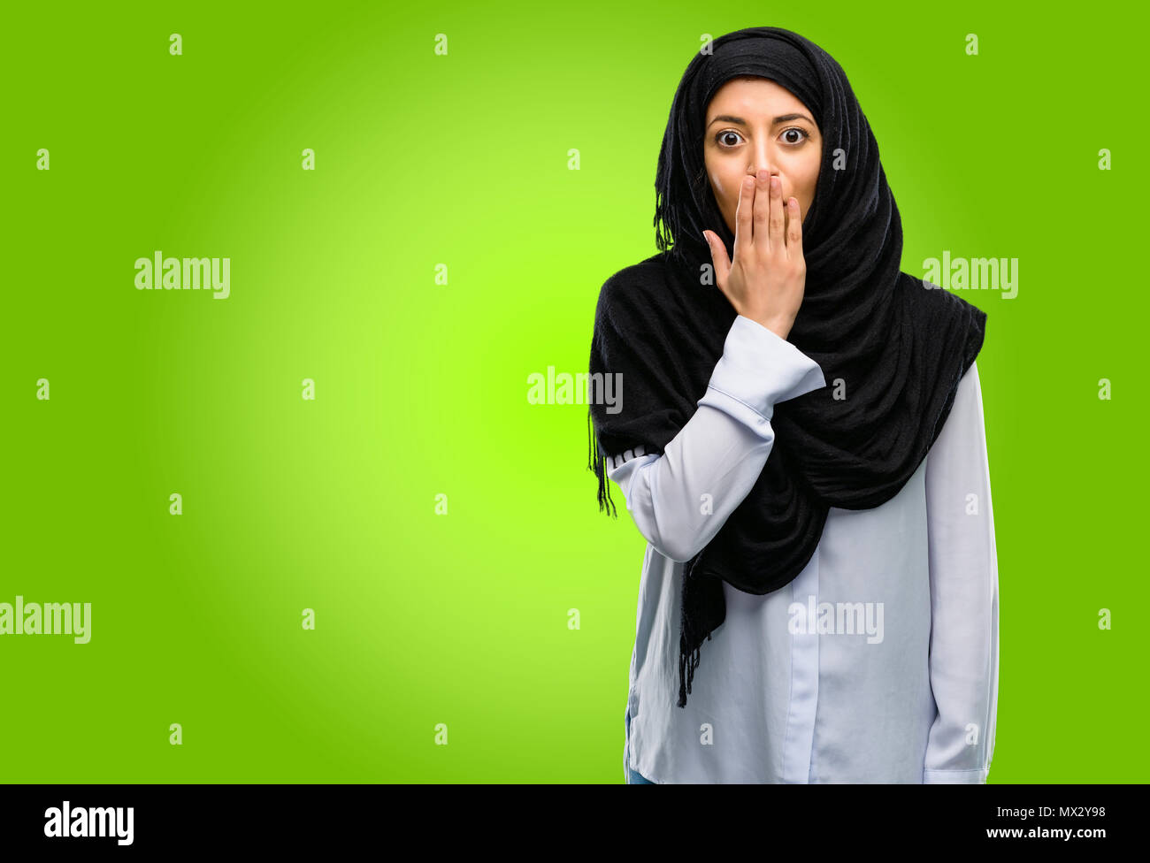 Joven árabe mujer vistiendo el hijab cubre boca en estado de shock, parece tímido, expresando el silencio y confundir los conceptos, asustada Foto de stock