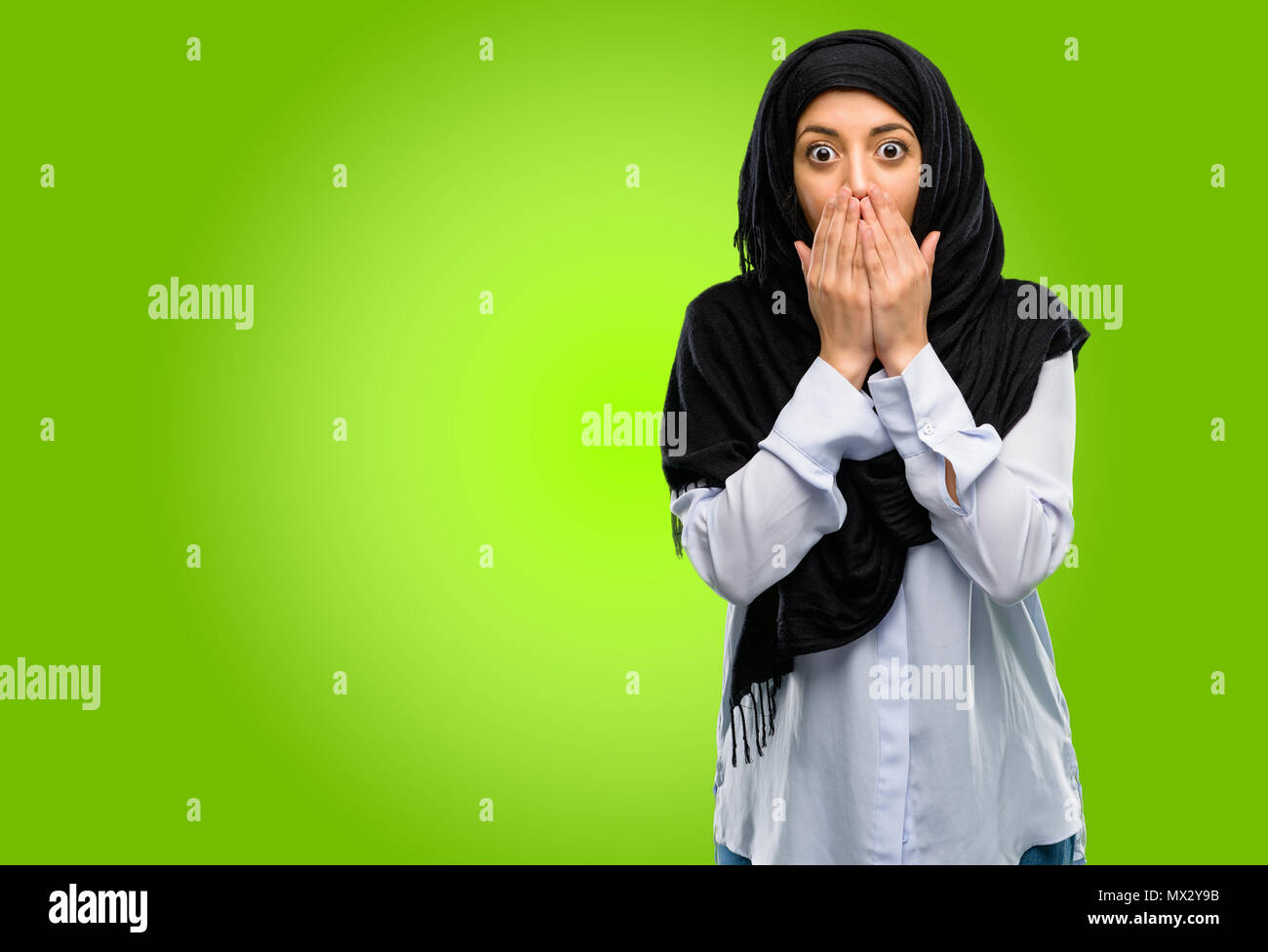 Joven árabe mujer vistiendo el hijab cubre boca en estado de shock, parece tímido, expresando el silencio y confundir los conceptos, asustada Foto de stock
