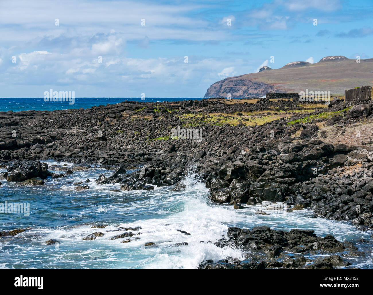 Olas rompiendo en la orilla rocosa con vista de Poike volcán extinto, Isla de Pascua, Rapa Nui, Chile Foto de stock