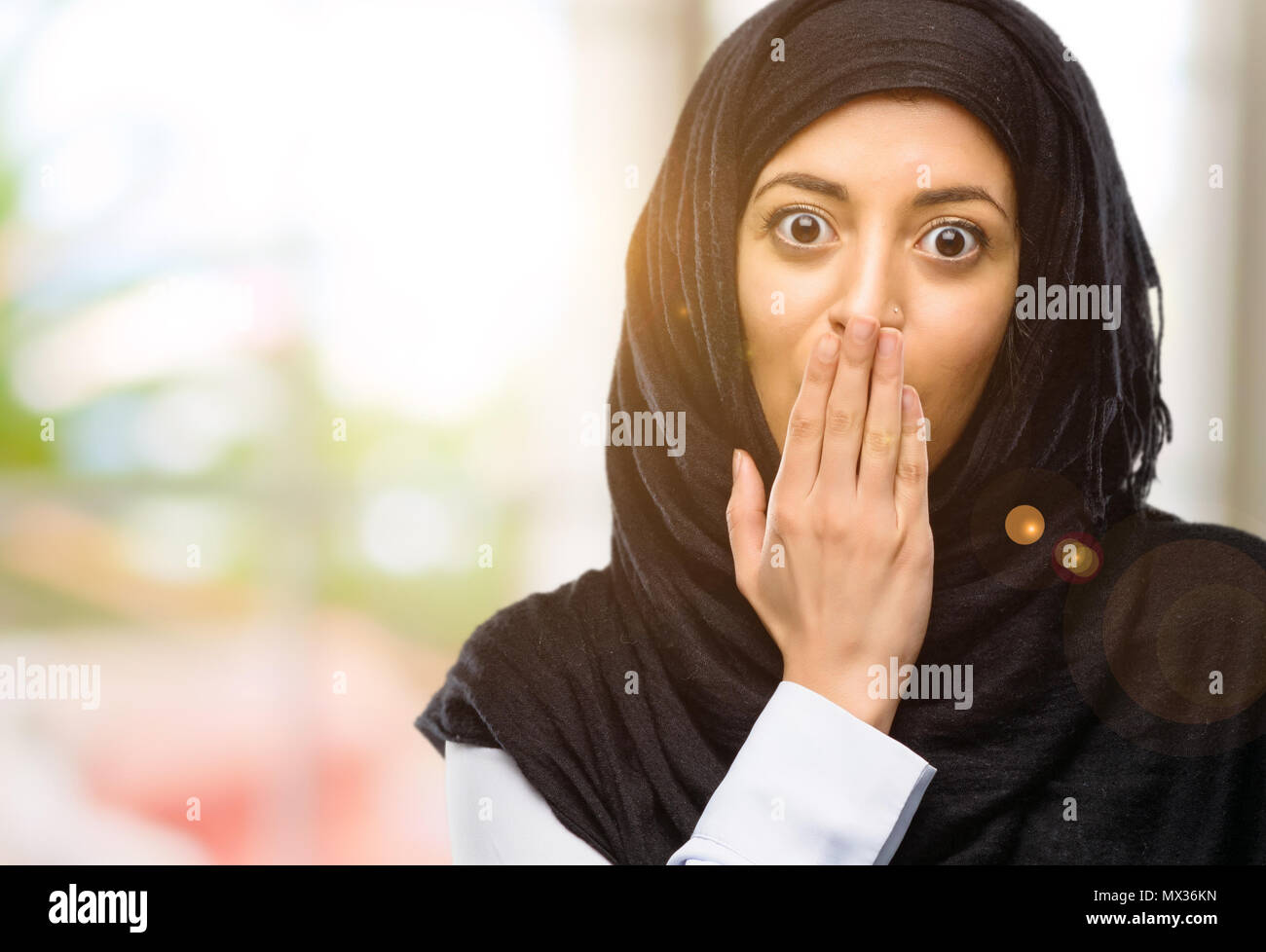 Joven árabe mujer vistiendo el hijab cubre boca en estado de shock, parece tímido, expresando el silencio y confundir los conceptos, asustada Foto de stock