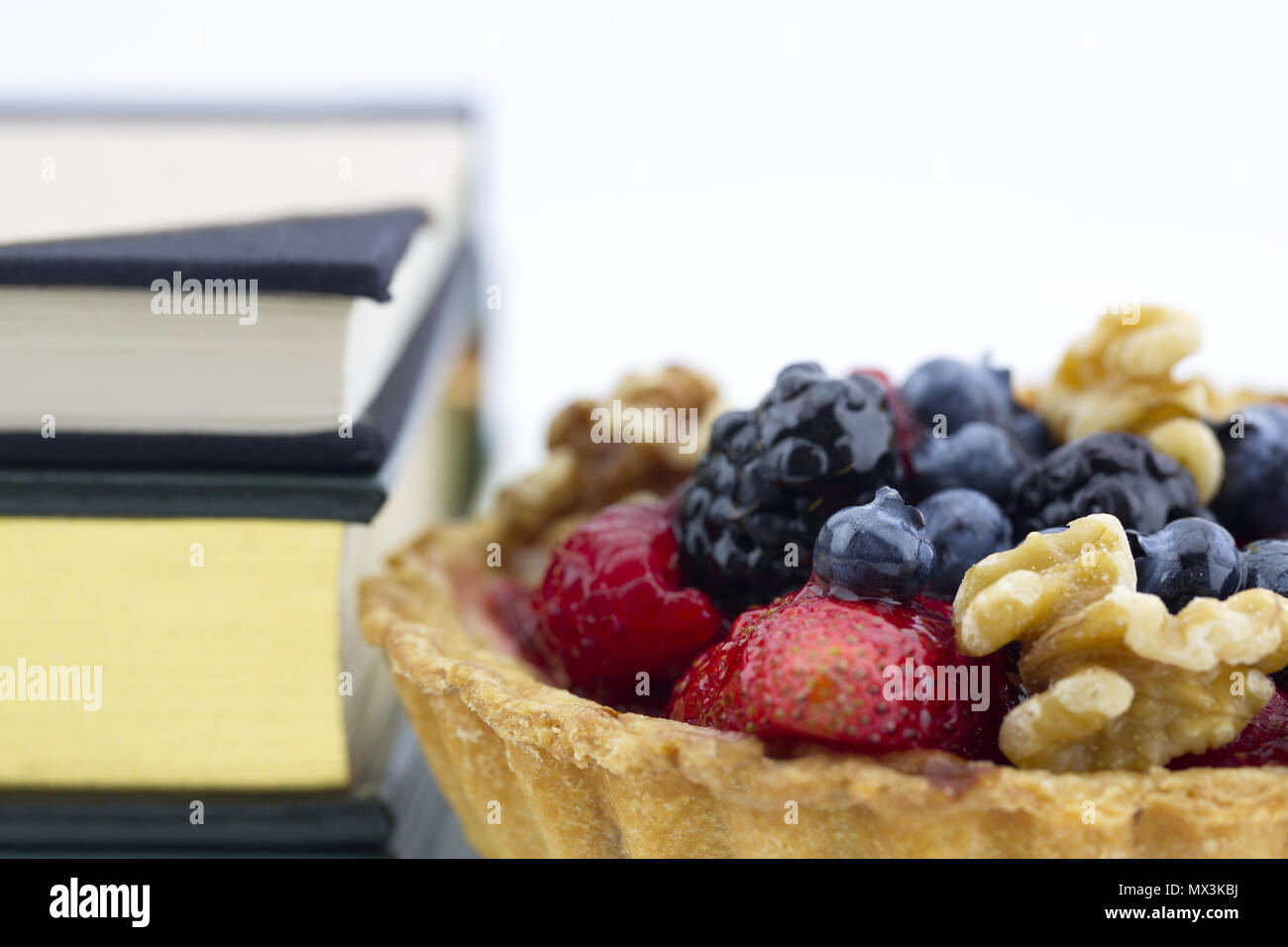 Tarta de frutas saludables colocados con libros en antecedentes sugieren fitness inteligente comiendo mientras estudiaba y en la planificación de planes de comidas y alimentos para una buena salud Foto de stock