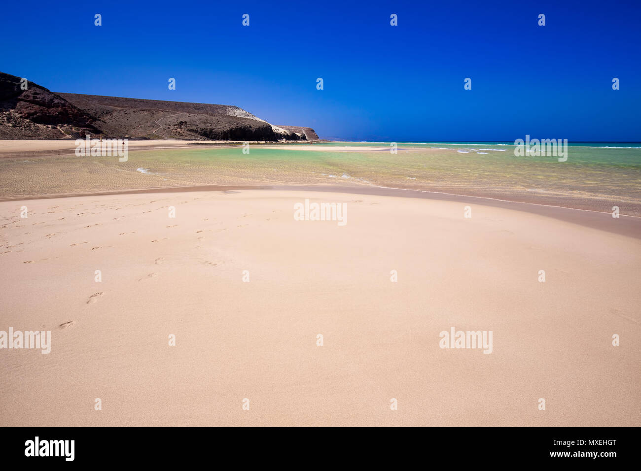 Playa de arena con montañas volcánicas y laguna verde en la isla de Fuerteventura, Islas Canarias, España, Europa. Foto de stock