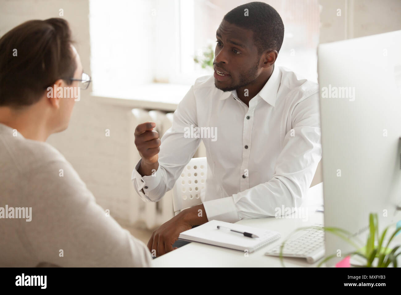Mentor afroamericano explicando la nueva idea Caucasian employe Foto de stock